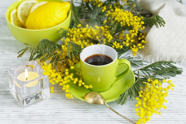 Mimosa, lemon and coffee on light wooden table