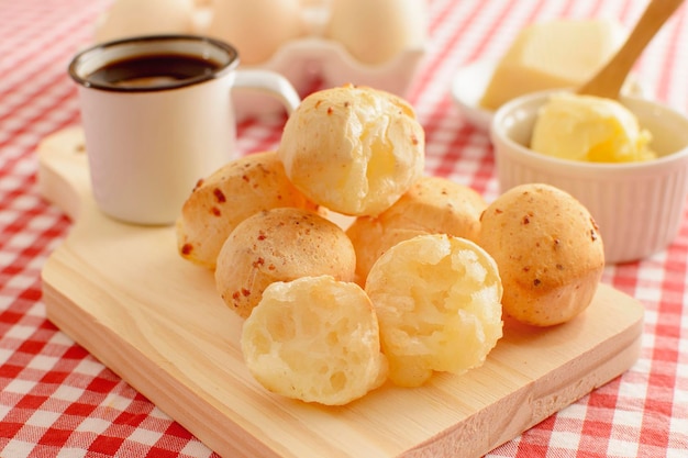 Pane al formaggio minas gerais caldo con una tazza di caffè nero e tovaglia da picnic a scacchi con burro