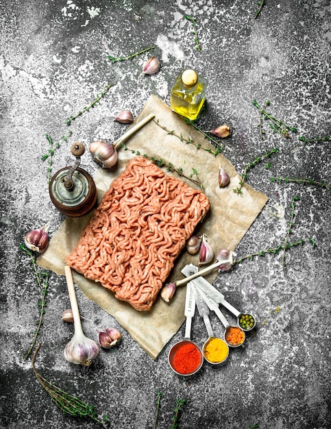 Minced beef with spices, aromatic herbs and olive oil on a rustic background