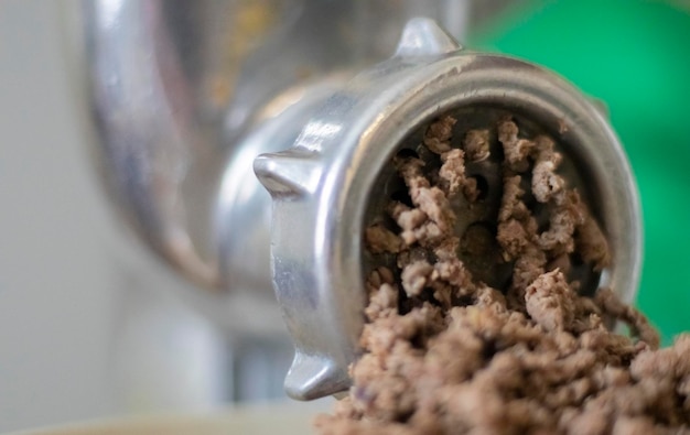 Minced meat in a manual mechanical meat grinder Fresh boiled meat is ground with an old metal meat grinder closeup in the kitchen