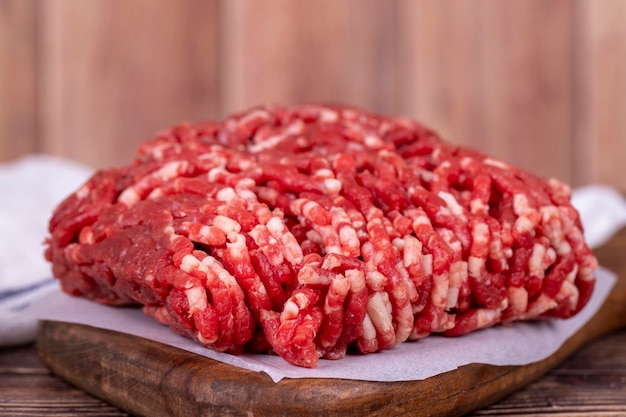 Фото Мелое мясо на деревянном фоне сырое мелое говяжие мясо или измельченное мясо