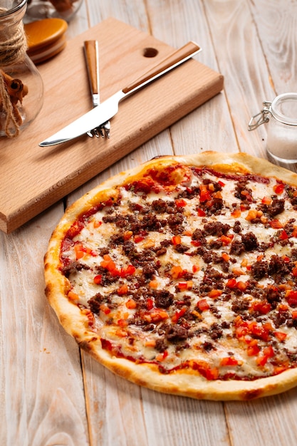 Minced meat pizza on the rustic wooden surface