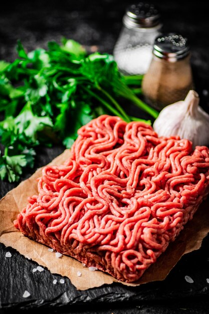 Minced meat on a stone board with parsley and garlic