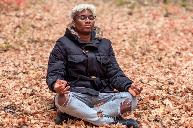 Mindful harmony and relax concept young black man breathing fresh air with eyes closed meditating in