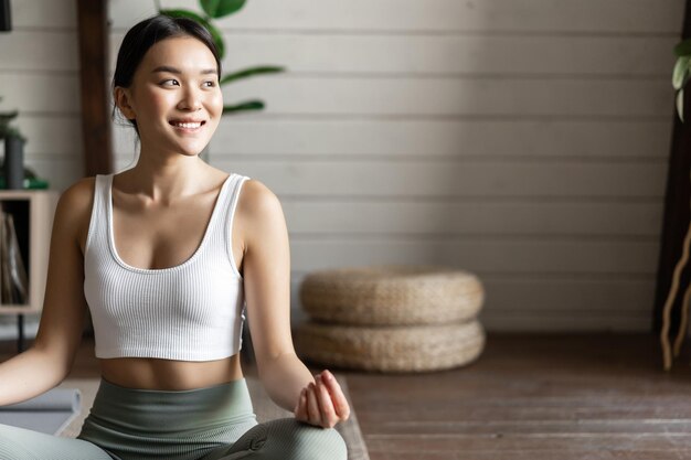 Mindfulness and meditation concept young asian woman doing workout at home yoga meditation in living...