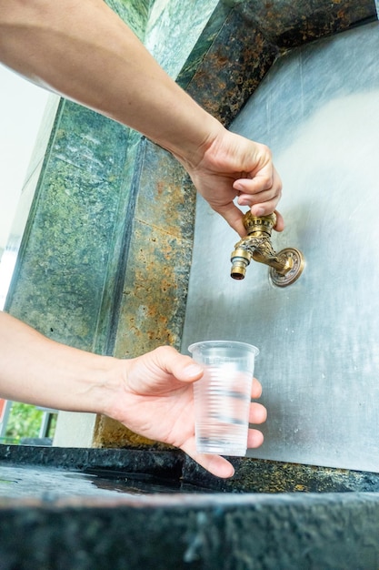 Mineraal thermaal water gieten in de wegwerpbeker bij de pompkamerclose-up