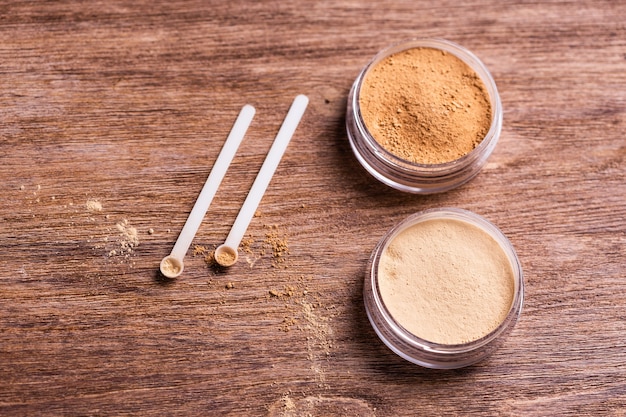 Mineral powder of different colors with a spoon dispenser for makeup on wooden background