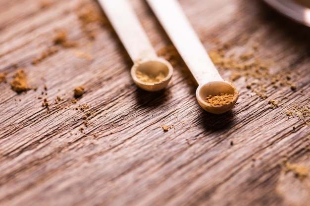 Mineral powder with a spoon dispenser for makeup on wooden background