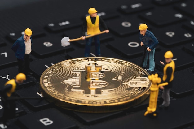 Miners miniature figures mining golden bitcoins on computer keyboard for cryptocurrency investment trading by block chain technology concept