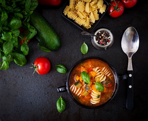 Minestrone, italian vegetable soup with pasta on black backgrounds.