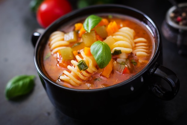 ミネストローネ、黒い背景にパスタとイタリアの野菜スープ。