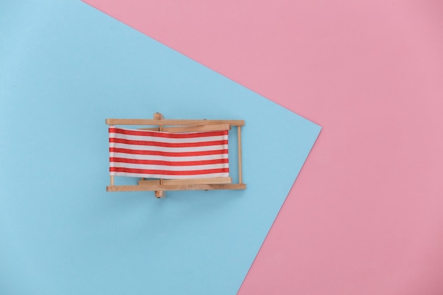 Foto mini sedia da spiaggia su sfondo blu-rosa pastello. vista dall'alto