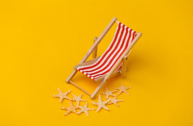 Foto mini sdraio da spiaggia e stelle marine su giallo. simbolo delle vacanze al mare, resort