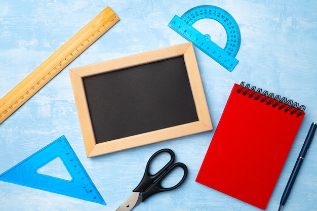 Mini blackboard in wooden frame and school supplies top view