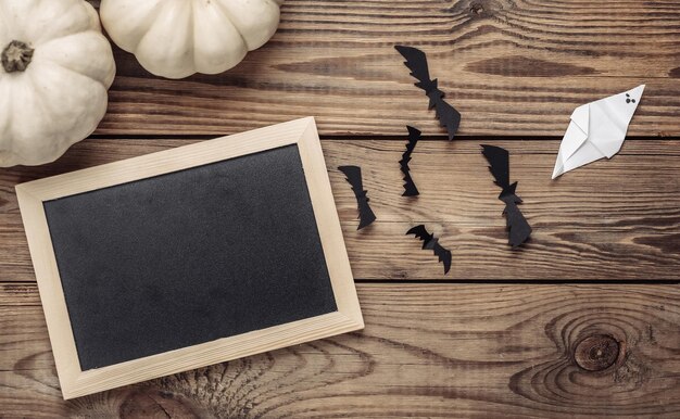 Mini blank chalk board with copy space and halloween decor on wooden table Trick or treat Flat lay