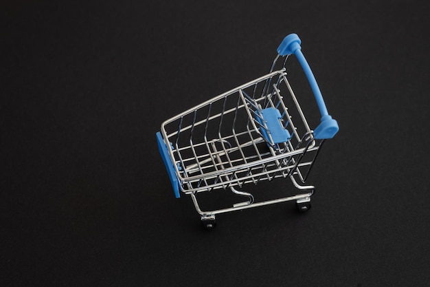 Mini blauwe supermarkt trolley op zwarte achtergrond Shopping concept