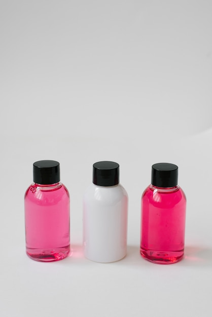 Mini bottles of pink and white color with body care cosmetics or hair on white background