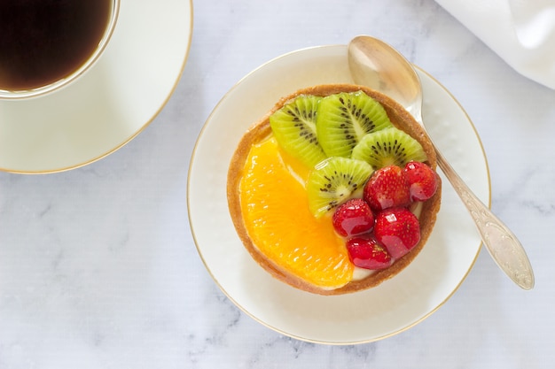 Mini cake or tart with custard and various fruits in jelly.