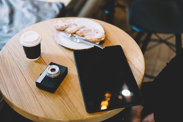 デジタルタブレットとテーブルの上の軽食とコーヒーのカップとミニカメラ