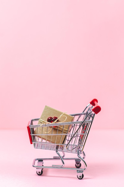 Mini cart and craft box with a red heart on a pink background