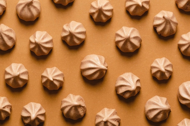 Mini chocolate meringue cookies on brown background