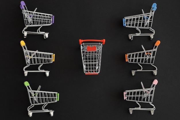 Mini color supermarket trolleys on black background Shopping concept