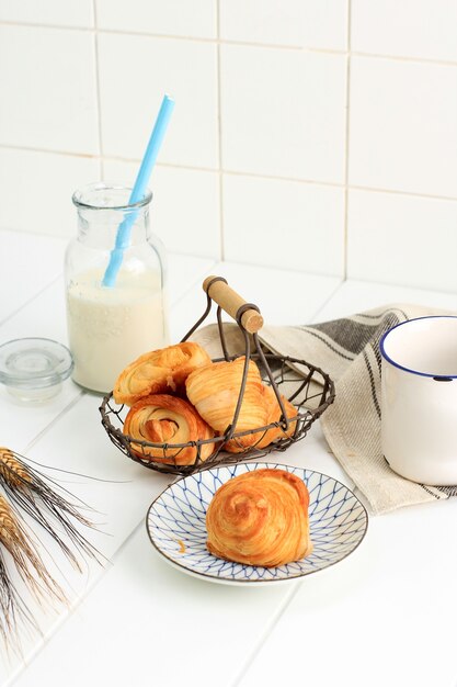 Mini Croissant with Milk, Flaky Pastry with Butter from French. Served on Plate and Woven Wire Basket on White Kitchen. Copy Space for Text.