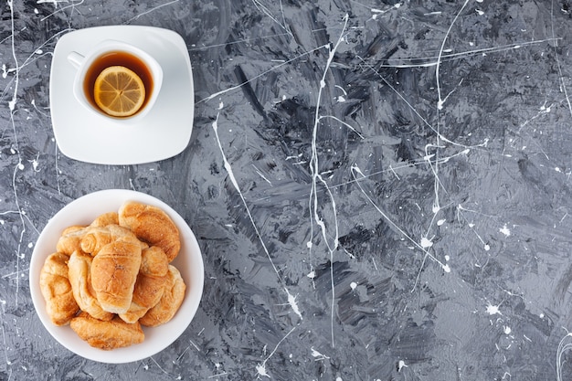 Foto mini cornetti di pasta sfoglia con crosta dorata e una tazza di tè.