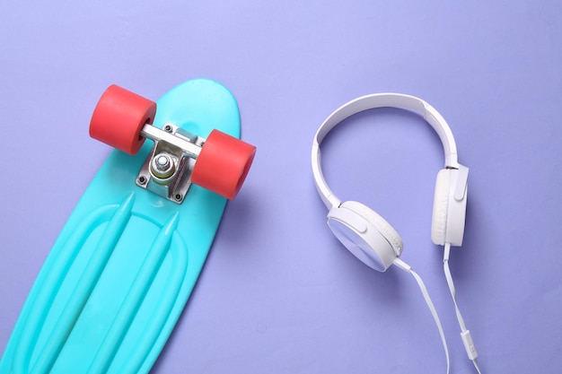 Mini cruiser board and stereo headphones on a purple background Youth concept Top view