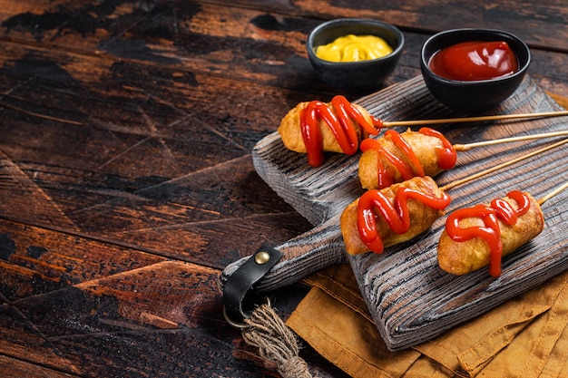 Mini Deep fried corn dogs with mustard and ketchup on wooden board Wooden background Top view Copy space
