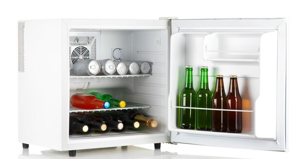 Mini fridge full of bottles of alcoholic beverages isolated on white