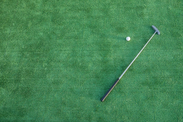 Photo mini golf equipment, golf club and ball on green ground