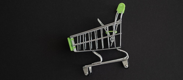 Mini groene supermarkt trolley op zwarte achtergrond Shopping concept