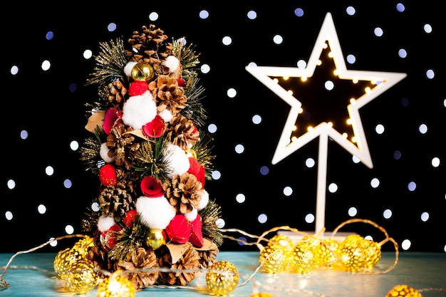Mini kerstboom en een ster op de achtergrond op feestelijk bokehlicht. Decoratie en vakantie. Seizoensgebonden en nieuwjaar