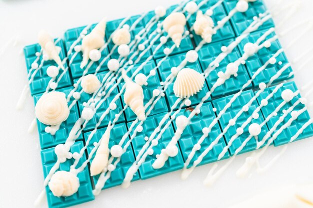 Foto mini barrette di cioccolato a forma di sirena ricoperte di cioccolato bianco, cosparse di granelli di zucchero bianco perla e decorate con conchiglie di cioccolato bianco.