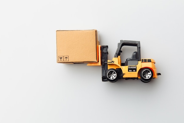 Mini model of forklift with carton box isolated on white. Logistics and delivery concept. Top view