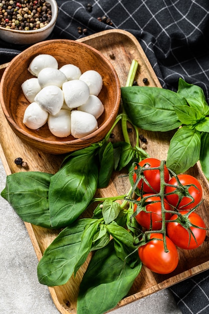 Mini mozzarella cheese, Basil leaves and cherry tomatoes, cooking Caprese salad. gray background. top view