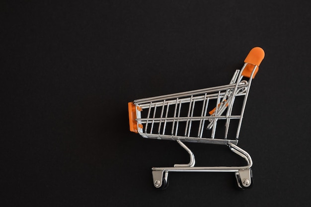 Mini orange supermarket trolley on black background Shopping concept