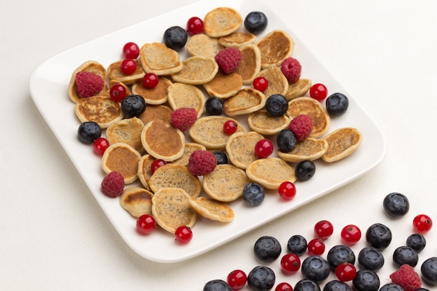 Mini pancakes and berries in plate. Red currants, blueberries