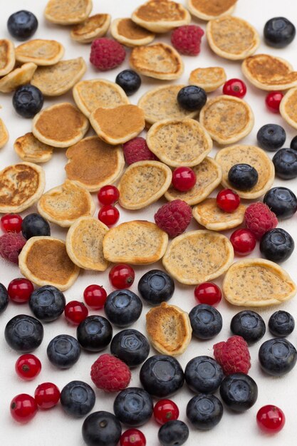 Mini pancakes and berries on white table