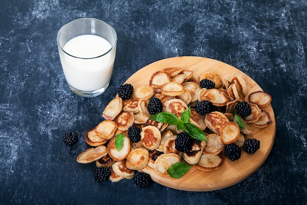 Mini-pancakes and blackberries, a glass of milk. Dessert.