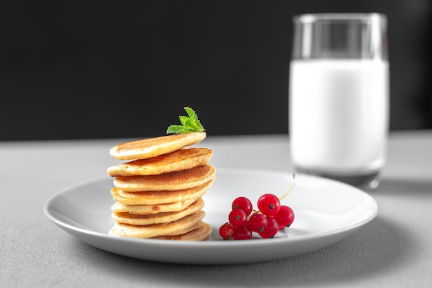 Mini pancakes with blueberries and raspberries American breakfast on a dark background