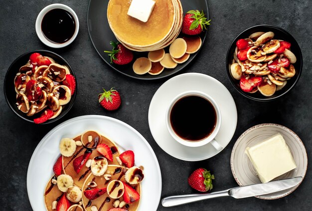 Mini pancakes with strawberries and bananas on plates on the table