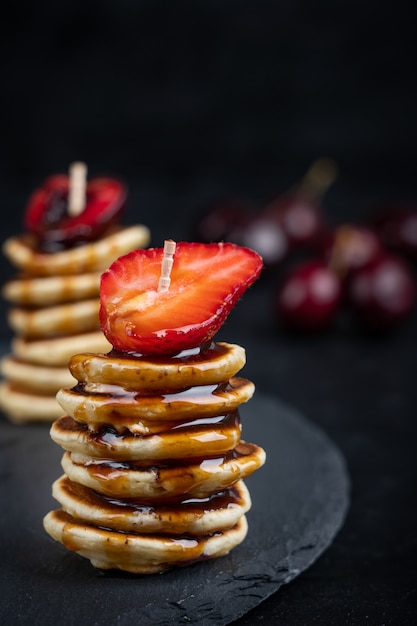 Mini pannenkoekjes in een stapel met aardbeien en karamelsiroop