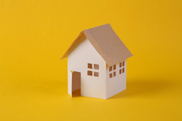 Mini paper house model on yellow background