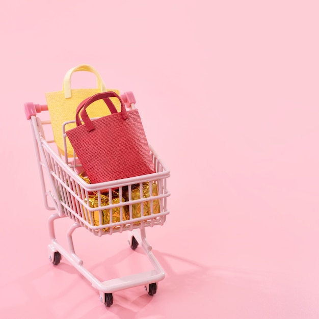 Mini pink shop cart trolley full of paper bag gift with copy space