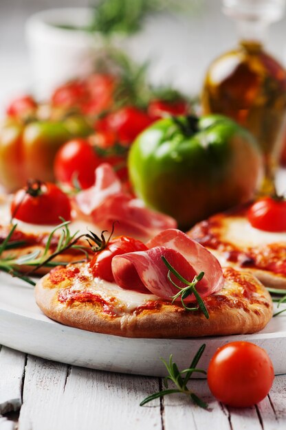 Mini pizza with mozzarella, prosciutto and tomato