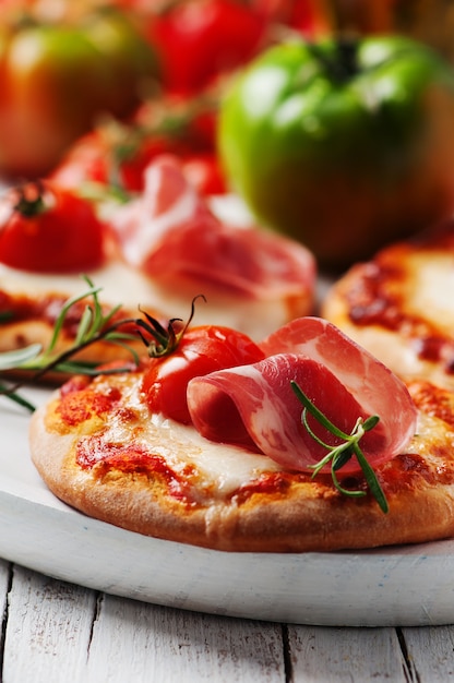 Mini pizza with mozzarella, prosciutto and tomato