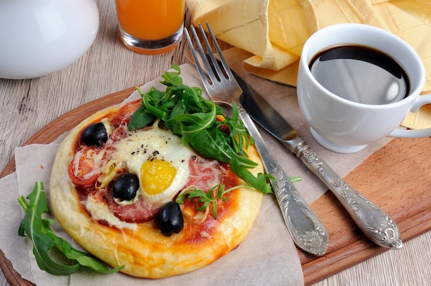 ソーセージと卵とルッコラのミニピザ朝食に一杯のコーヒー