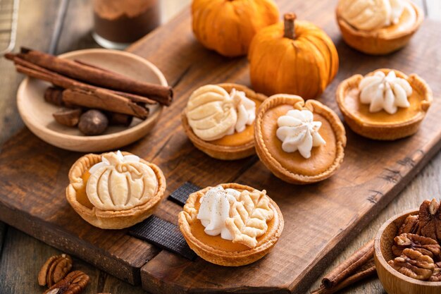 Photo mini pumpkin pies with wipped cream and cinnamon